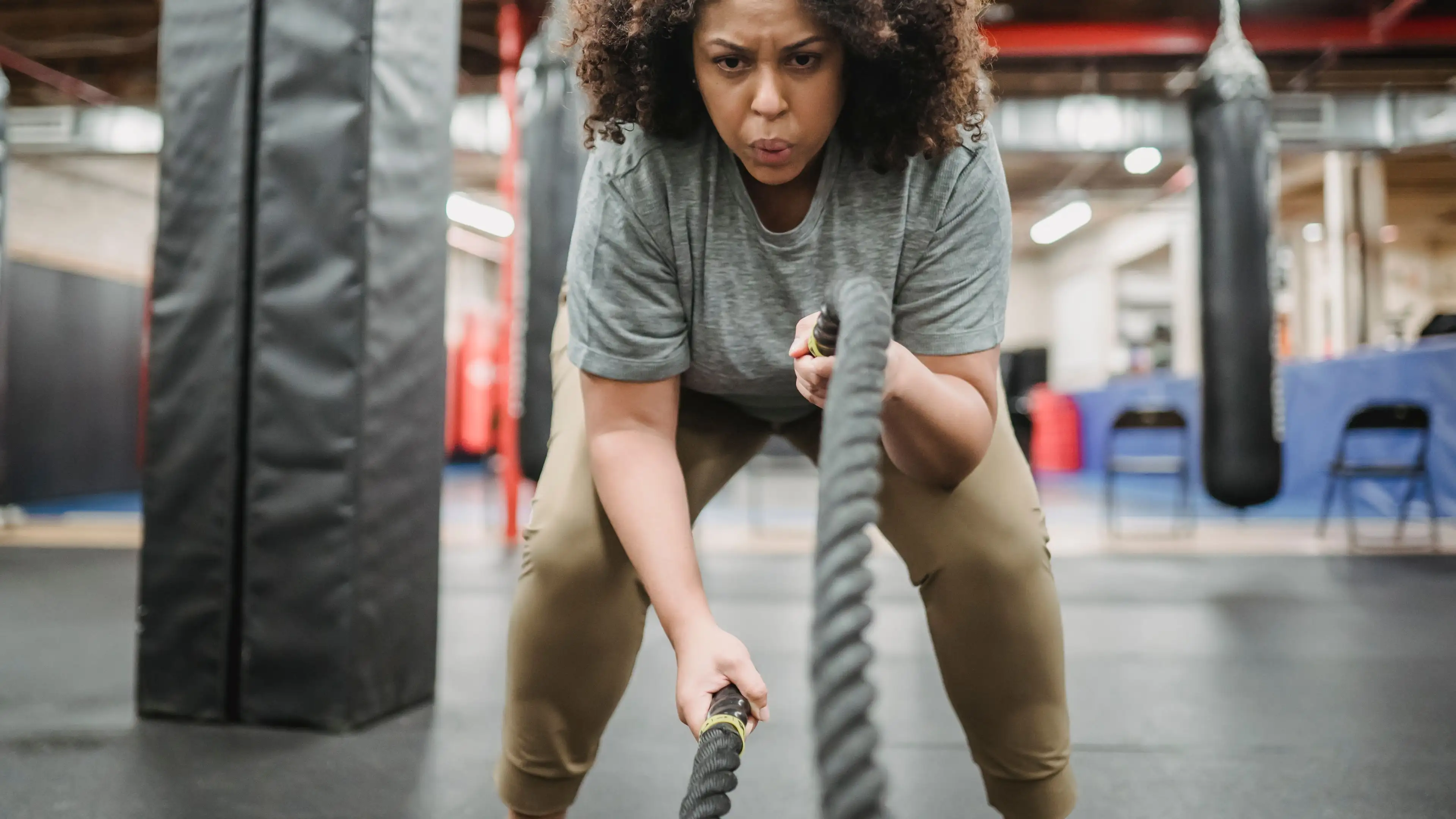 A determined woman training with battle ropes in a boxing gym